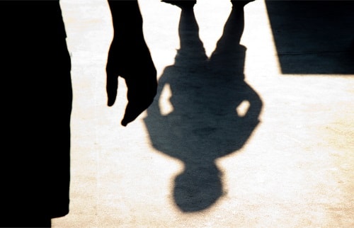 silhouette and shadow of a child being confronted by an ominous person