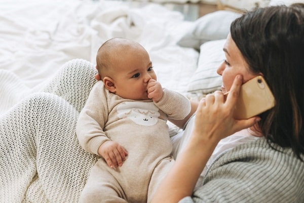 infant boy staring at mother while she talks on the phone