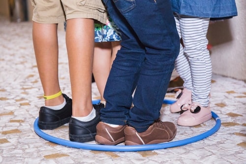 view of children's feet inside a hula hoop -- four different kids sharing a space in social skills activity