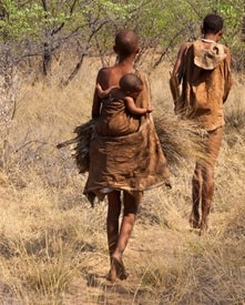 Kalahari San people, foragers returning home, mother carrying infant 
