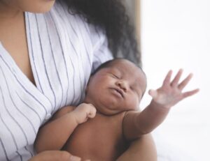 baby sleeping -- and reaching out with arm -- while being held