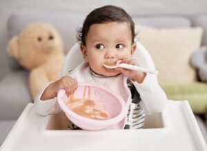 baby using spoon to eat