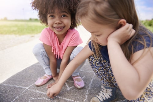 two young girls - friends - writing with chalk on sidewalk - hopscotch