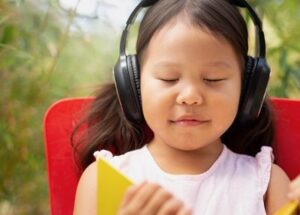 young girl listening to music with headphones, eyes closed