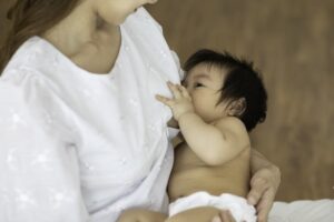 infant breastfeeding, faces partially covered by infant's head
