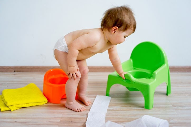 baby approaching potty chair, leaning over and looking in