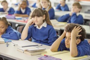 frustrated, reluctant students sit in class at desk