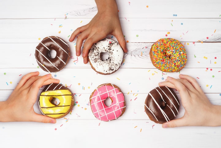 Children's hands reaching for donuts
