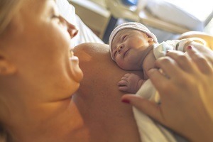 mother and newborn smiling at each other in hospital bed