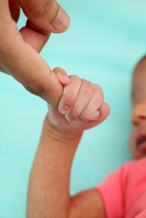 closeup of newborn hand grasping adult finger