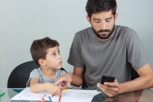 phubbing father is ignoring young son next to him, son is trying to get his attention