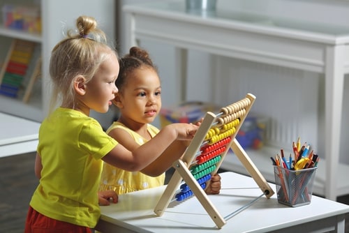 Two preschool girls playing together with an abacus