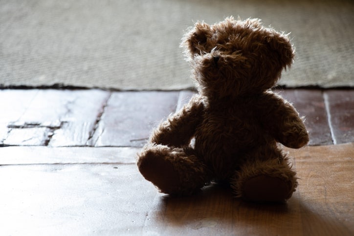 lonely-looking teddy bear sitting in the shadows