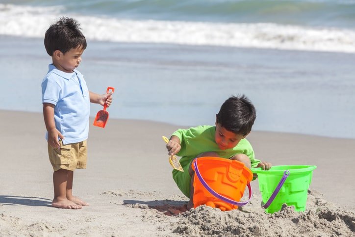 two young boys making sandcastles on the beach