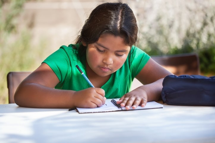 focused young girl writing at desk