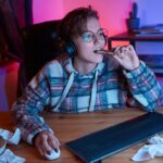 teen at compuer is eating sugary, late night snack