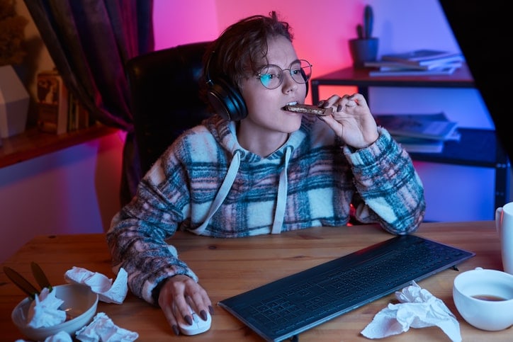 teen working at a computer and eating a sugary, late night snack