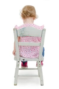 toddler seated on chair, back to viewer