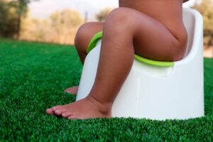kid sitting on potty chair outside, seen from waist down