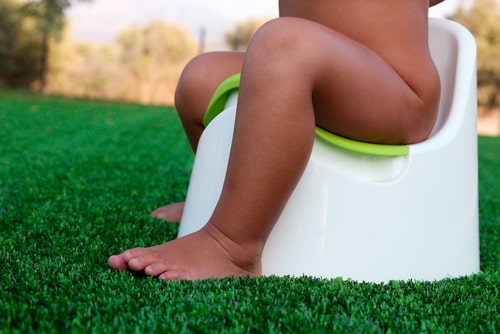 kid sitting on potty chair outside, see from waist down