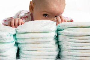 baby peaking through stacks of diapers