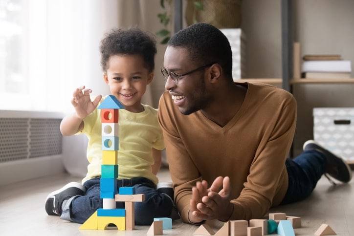 toddler and father playing with building blocks on the floor