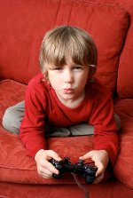 intense young boy playing video game on a couch