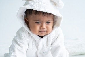 baby wearing white hoody looks worried
