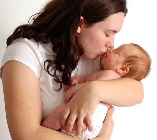 mother kissing newborn infant