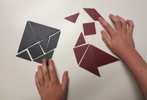 child's hands manipulating tangrams - by G. Dewar 2018