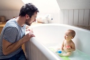 father talking to baby, baby is in the bathtub