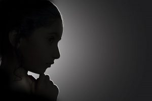 girl child with hand on chin portrait side view backlit